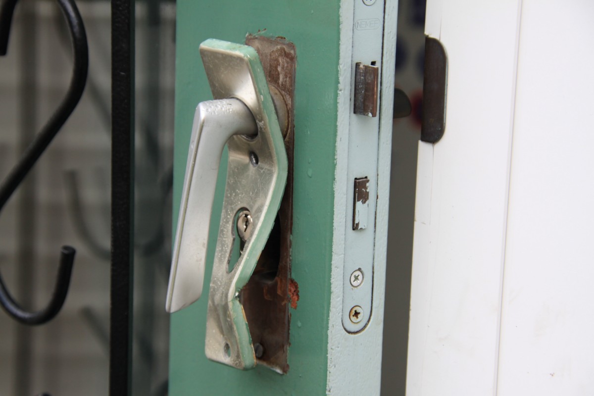 Beschadigde groene deur met verbogen deurbeslag na een inbraak